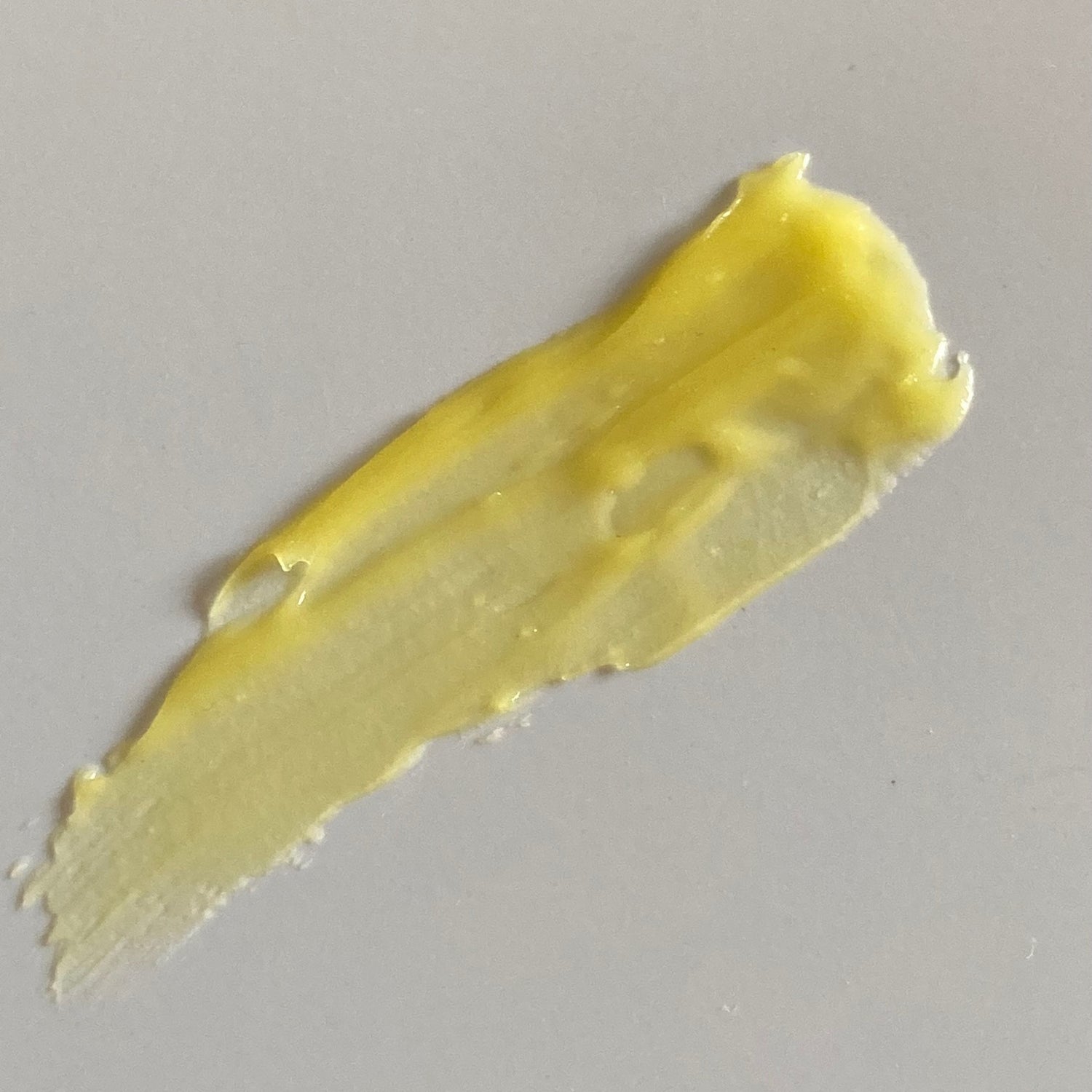 Smear of yellow Borage & Calendula Balm on white tile