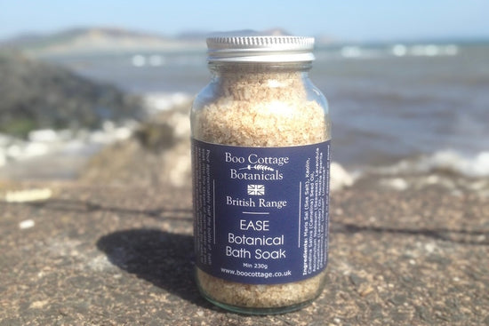 EASE bath soak in clear jar with blue label on sea wall with sea behind 