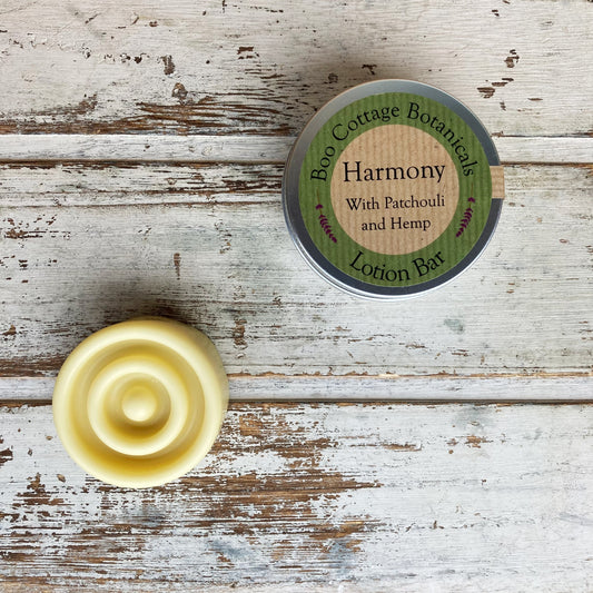 A lotion bar titled 'Harmony' with hemp and patchouli, presented next to its packaging, on a wooden surface.