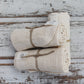 Pile of three rolled up cream organic cotton wash cloths on whitewashed wooden background