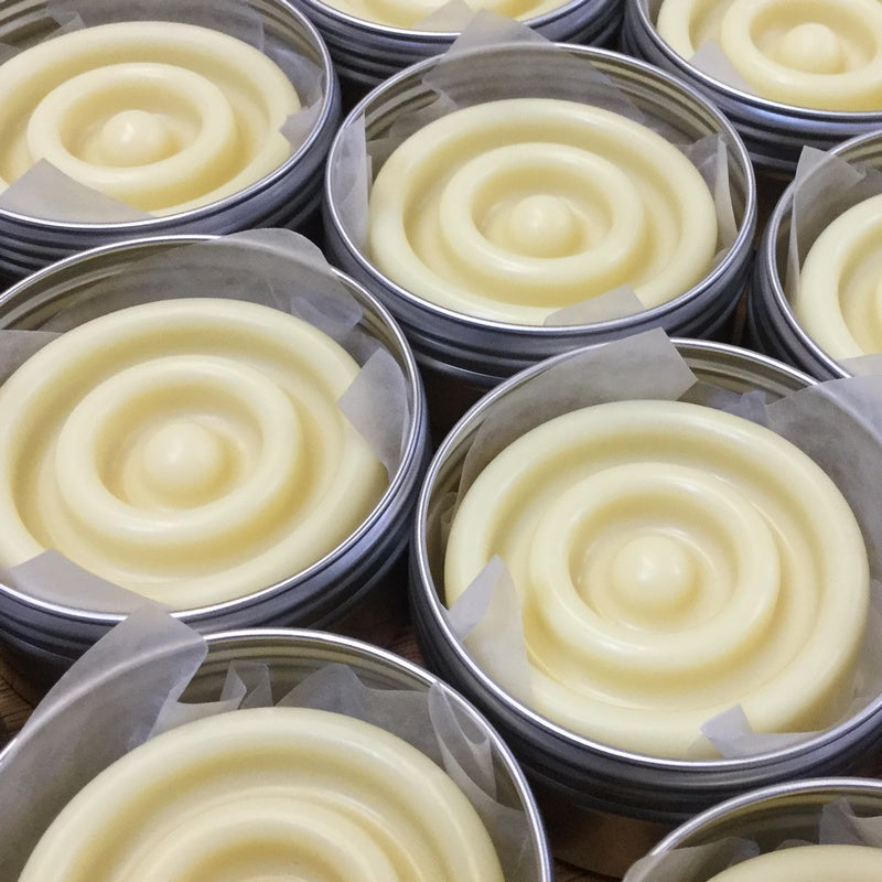 Collection of cream solid lotion bars in tins next to each other