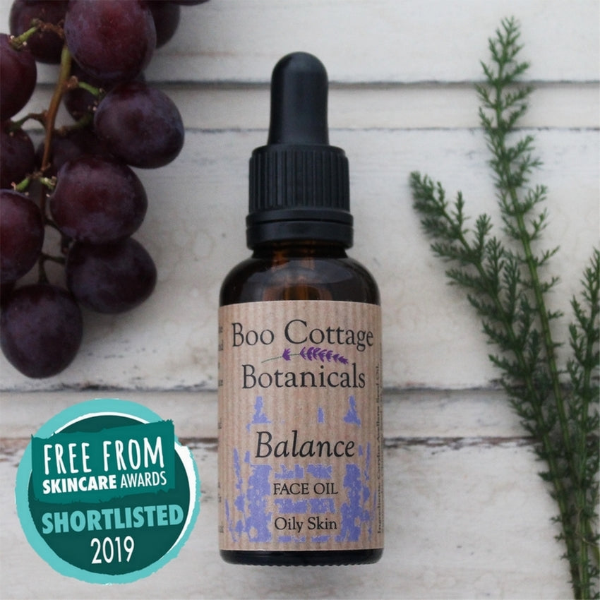 Balance face oil on whitewashed background with yarrow and black grapes with Free From Skincare award badge