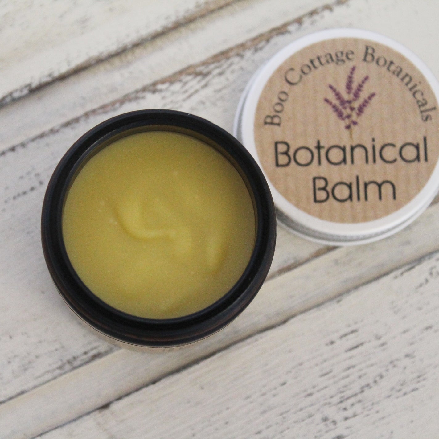 Cream jar of Botanical Balm on whitewashed wooden background