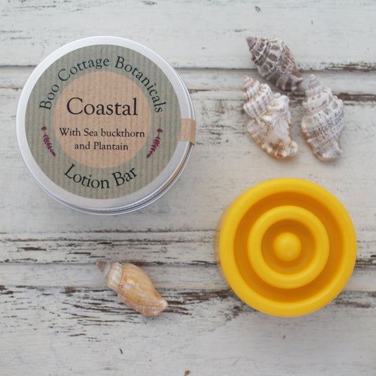 Yellow circular solid lotion bar with aluminium tin and sea shells on whitewashed wooden background