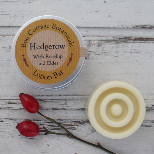 Cream circular solid lotion bar with round texture and aluminium tin on whitewashed background with rosehips