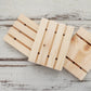 Pile of 3 natural pale wooden soap dishes with drainage grooves on whitewashed wooden background