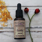 Amber bottle of Soothe face oil with black dropper pipette with rosehips and dried calendula petals on whitewashed wooden background