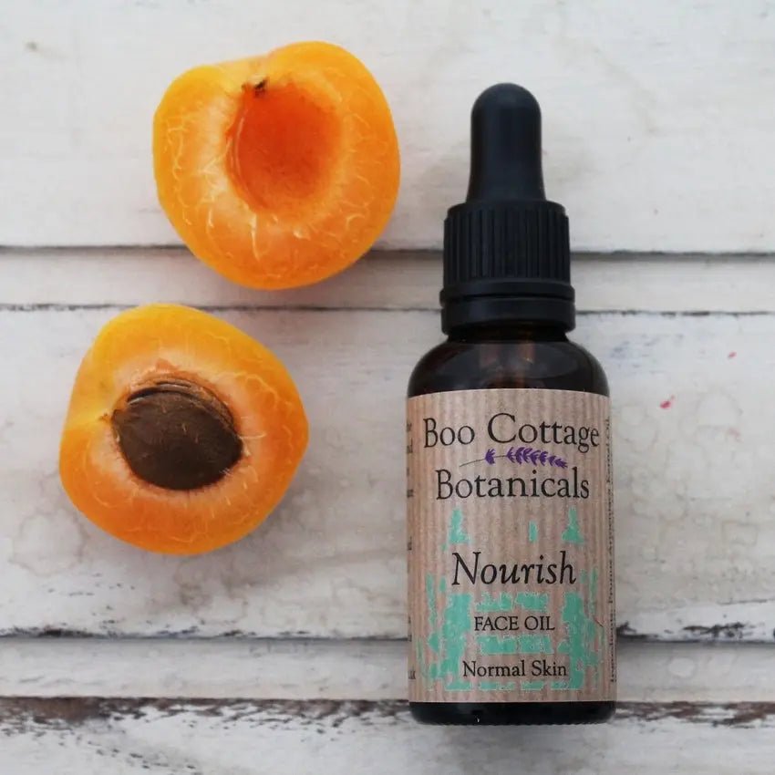 Nourish face oil in amber bottle with orange apricots on whitewashed wooden background