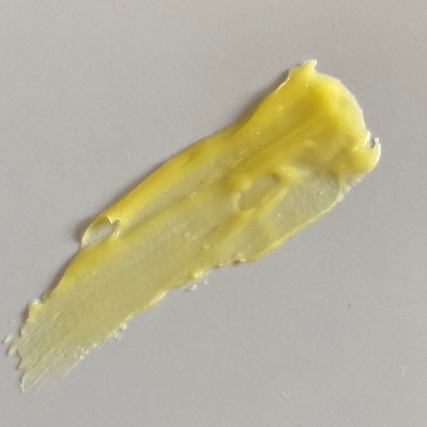 Smear of yellow balm spread onto grey background