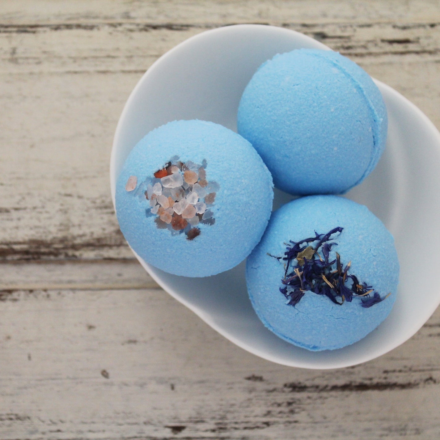 Blue bath bombs with lavender and salt toppings in white dish