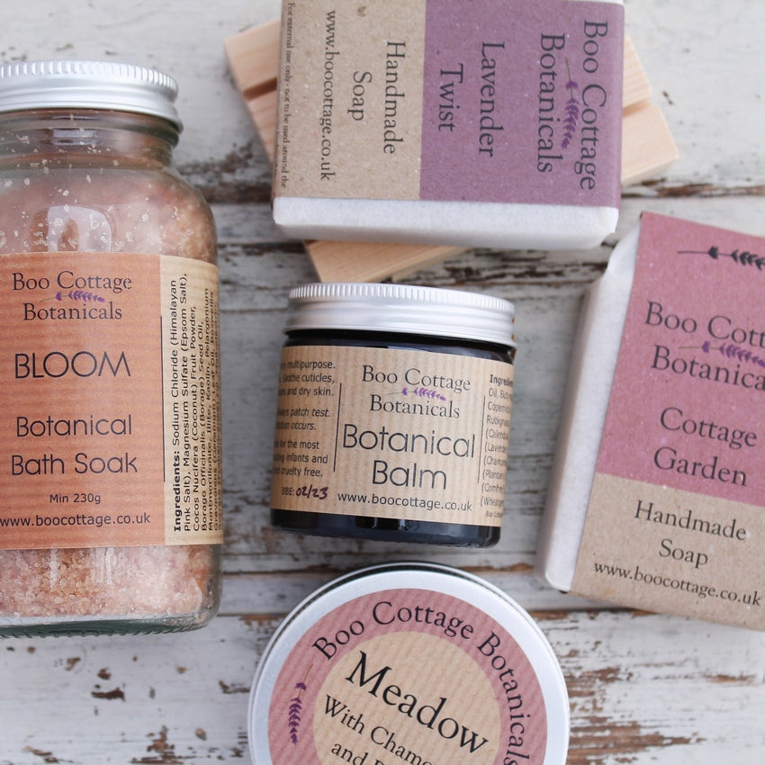 Close up of pink and purple themed labelled products on whitewashed wooden background