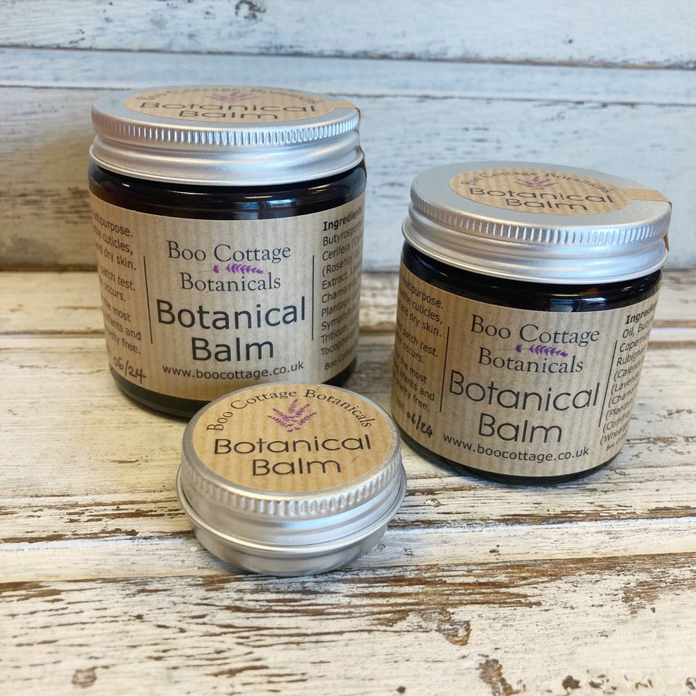 3 size options of Botanical Balm; Family size, Standard size and Sample tin on whitewashed wooden background