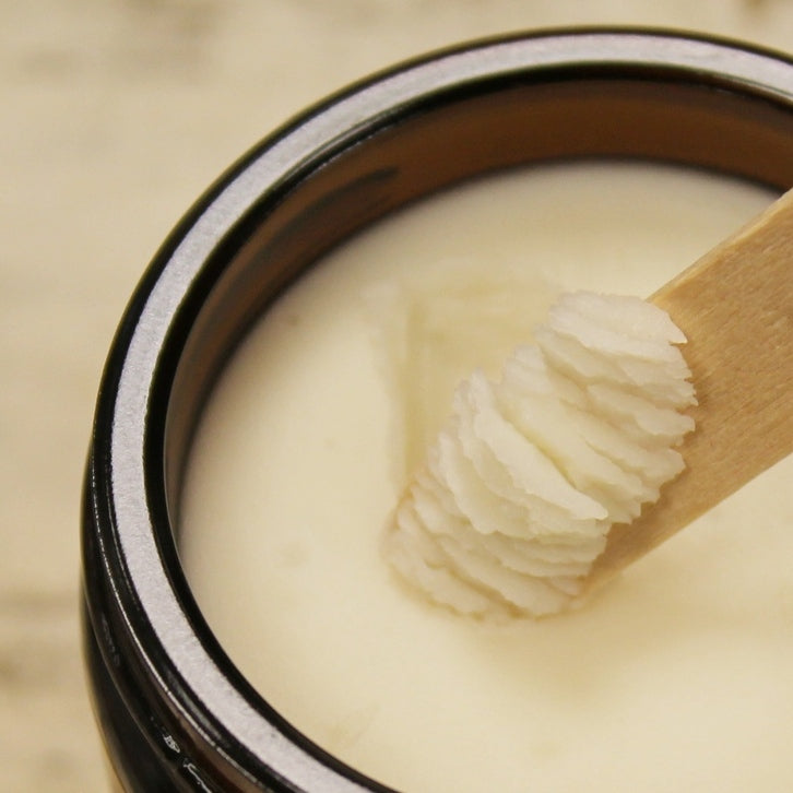 Close up of white chamomile cleansing balm showing texture of balm on scoop