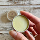 Cream chamomile cleansing balm sample in mini tin in hand with white background