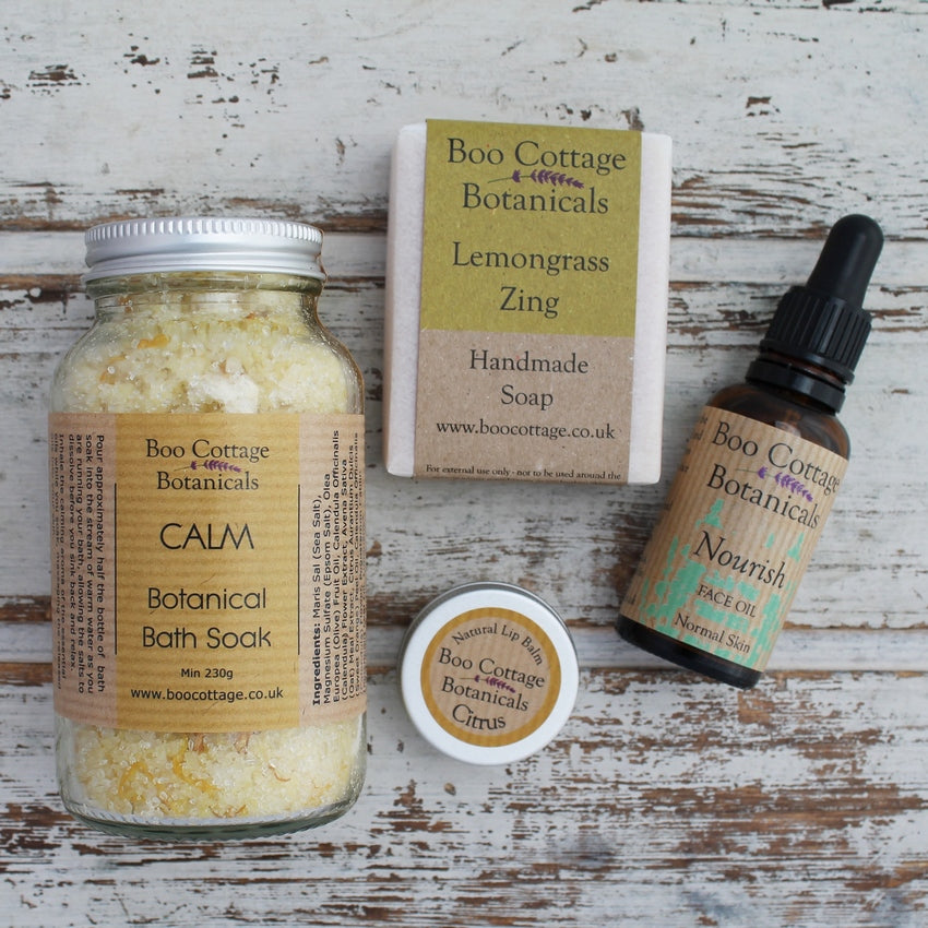 Yellow bath salts, soap bar, lip balm and face oil on whitewashed backgound