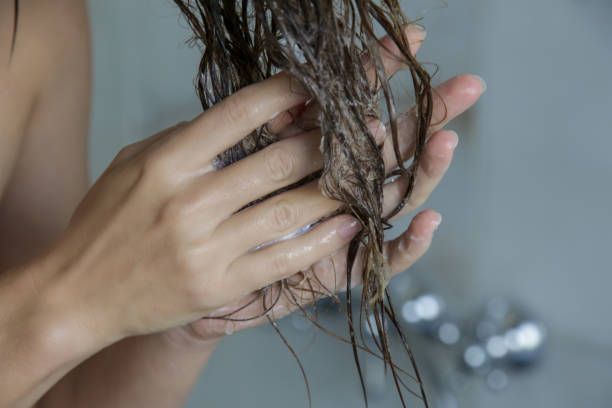 White hands applying conditioner to ends of hair