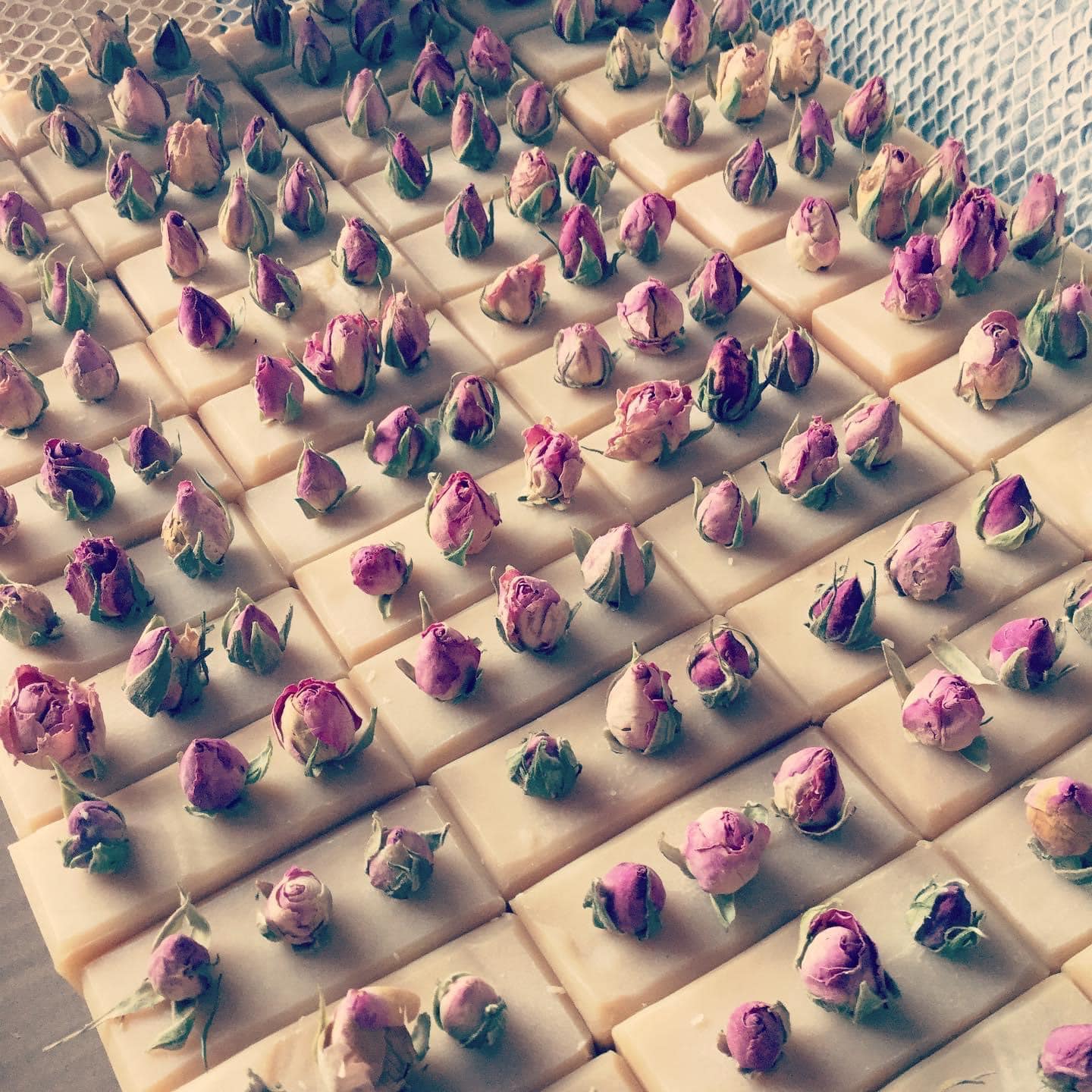 Collection of pink soaps with pink rose buds in top in a wire mesh drawer