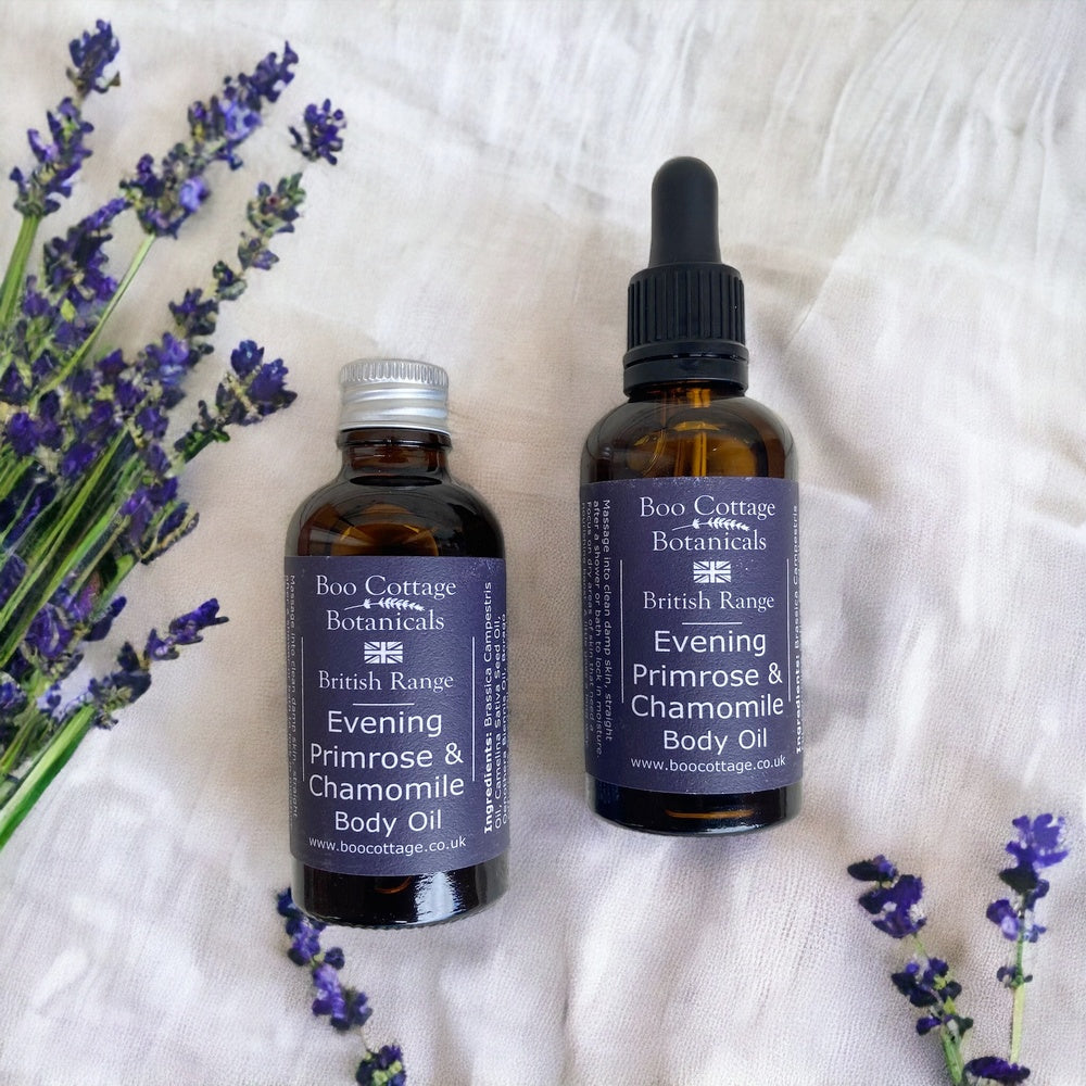 Amber bottles of evening primrose body oil with aluminium cap and dropper pipette on white fabric with lavender sprigs