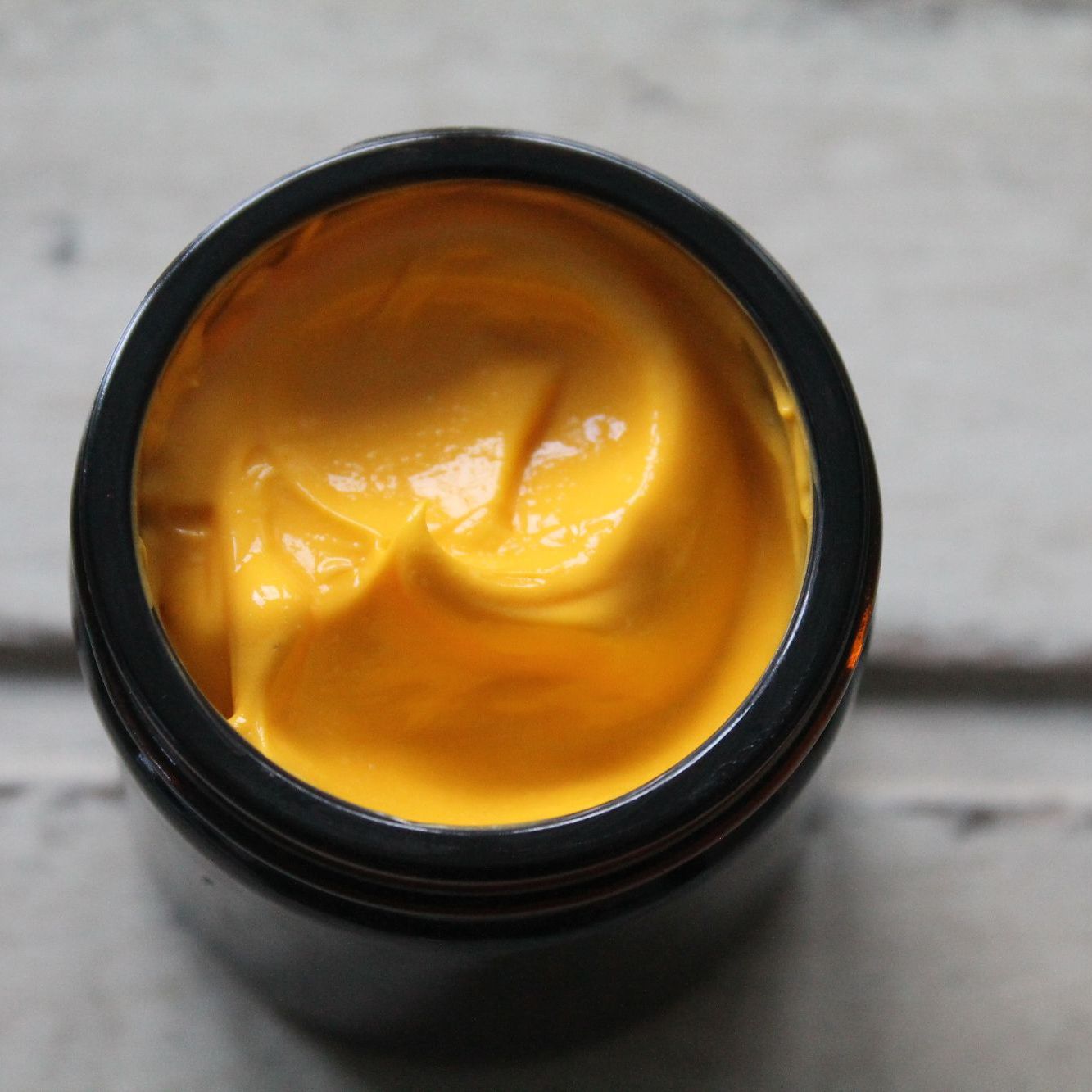 Yellow face cream in amber jar with white background