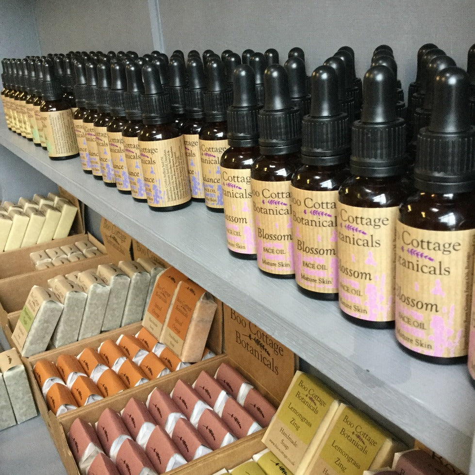 Bottles of face oils and wrapped soap bars on grey wooden dresser shelves