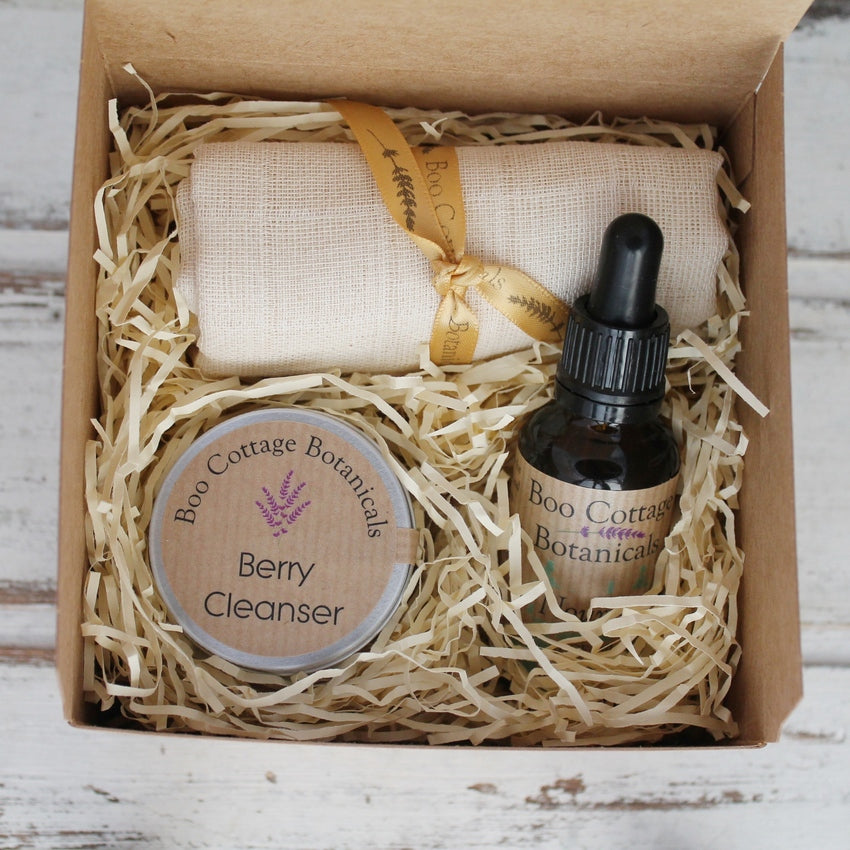 Cotton wash cloth, brown labelled jar and amber bottle in kraft card gift box with shredded cream paper