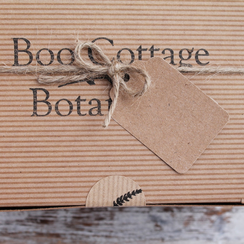 Close up of jute string bow and recycled brown card tag on striped brown box with Boo Cottage Botanicals stamp and round sticker