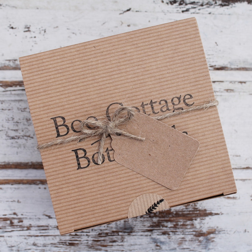 Square brown gift box with string and tag on whitewashed wooden background
