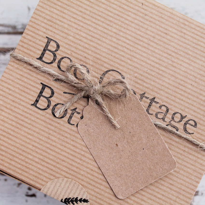 Close up of kraft gift box with Boo Cottage Botanicals stamp, with jute string bow and recycled card tag