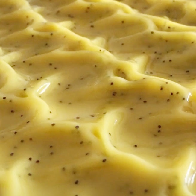 Glossy just poured top of yellow soap with poppy seeds showing soft scooped texture