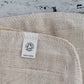 Close up of texture of cream cotton face cloth showing soil association organic label