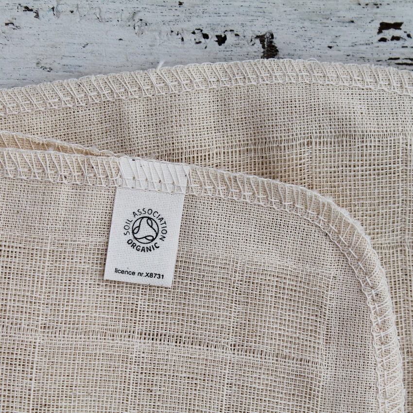 Close up of texture of cream cotton face cloth showing soil association organic label