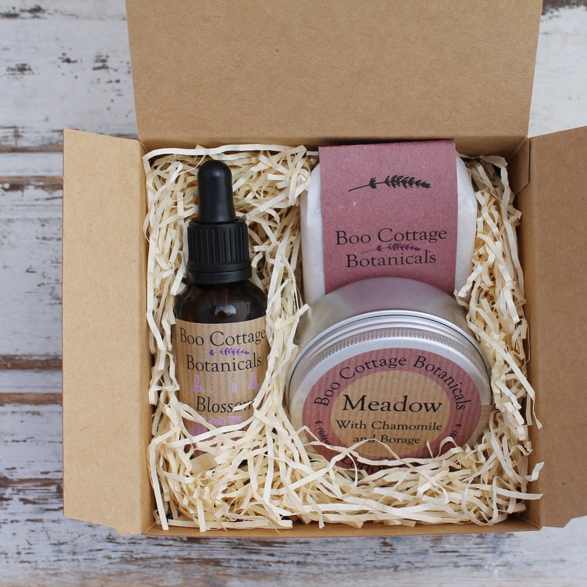 Kraft card gift box with cream shredded paper including Blossom face oil, pink Cottage Garden soap and Meadow lotion bar in tin