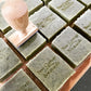Natural green soap bars with Boo Cottage Botanicals logo being stamped onto front of each bar with a wooden handled stamp