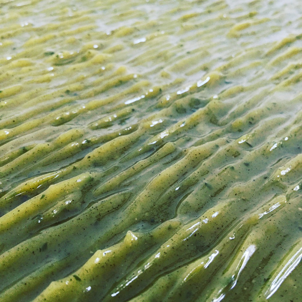 Glossy natural green soap slab freshly poured with wave like textured top