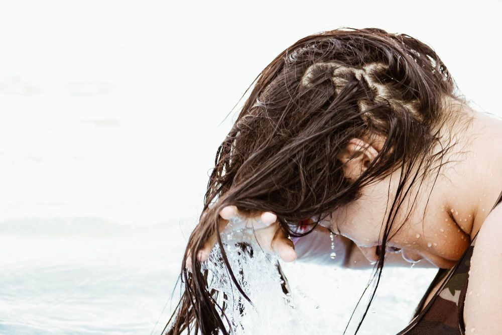 Brunette hair being rinsed out with sea in background