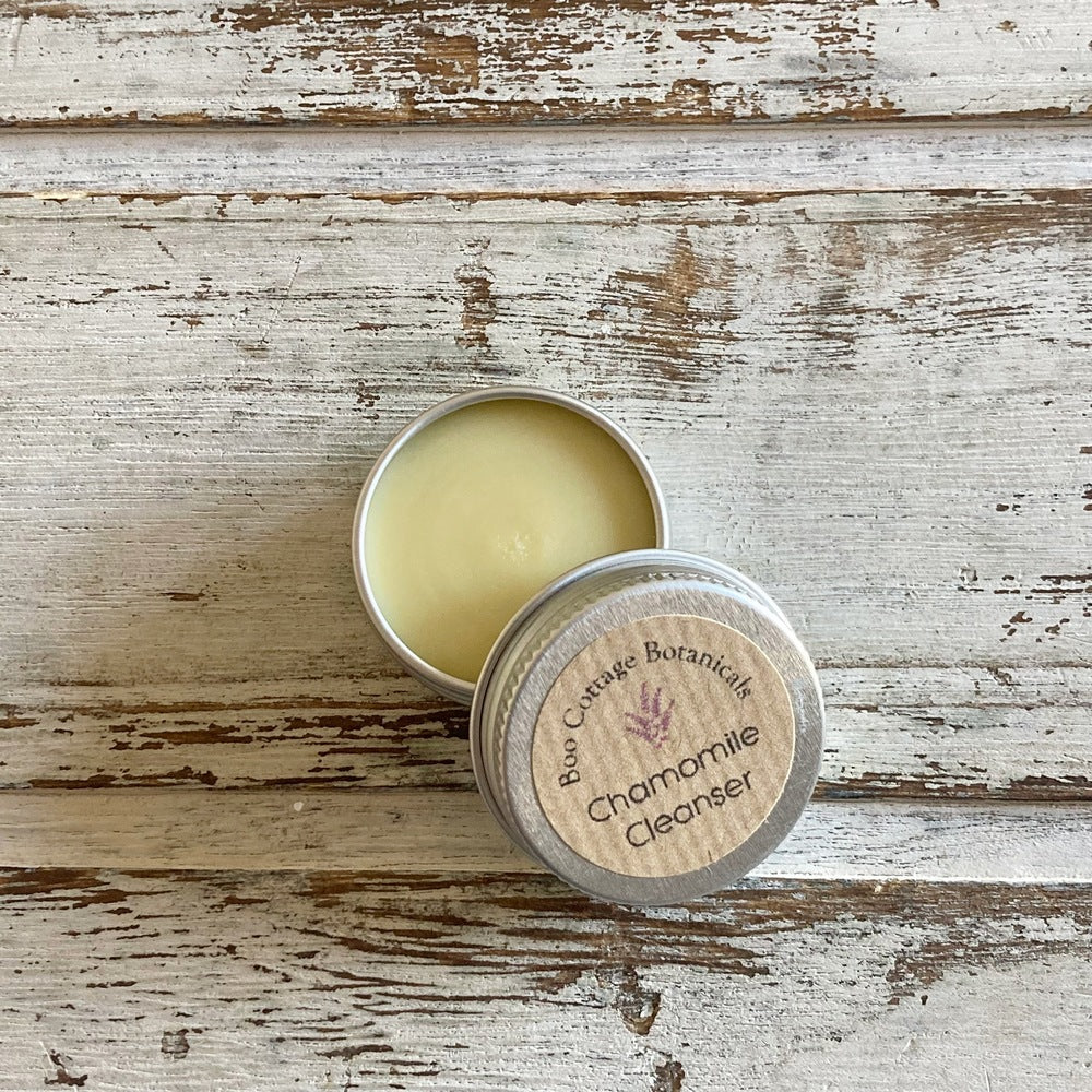 Cream coloured chamomile cleansing balm sample in mini tin with open lid on white background