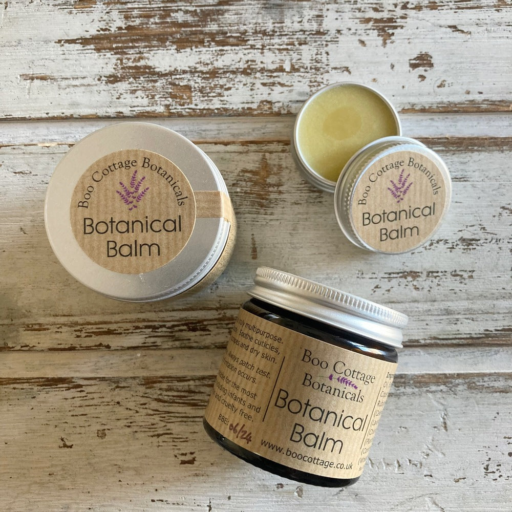 Amber jar with brown label and aluminium lid of Botanical Balm alongside sample sized tins on white background