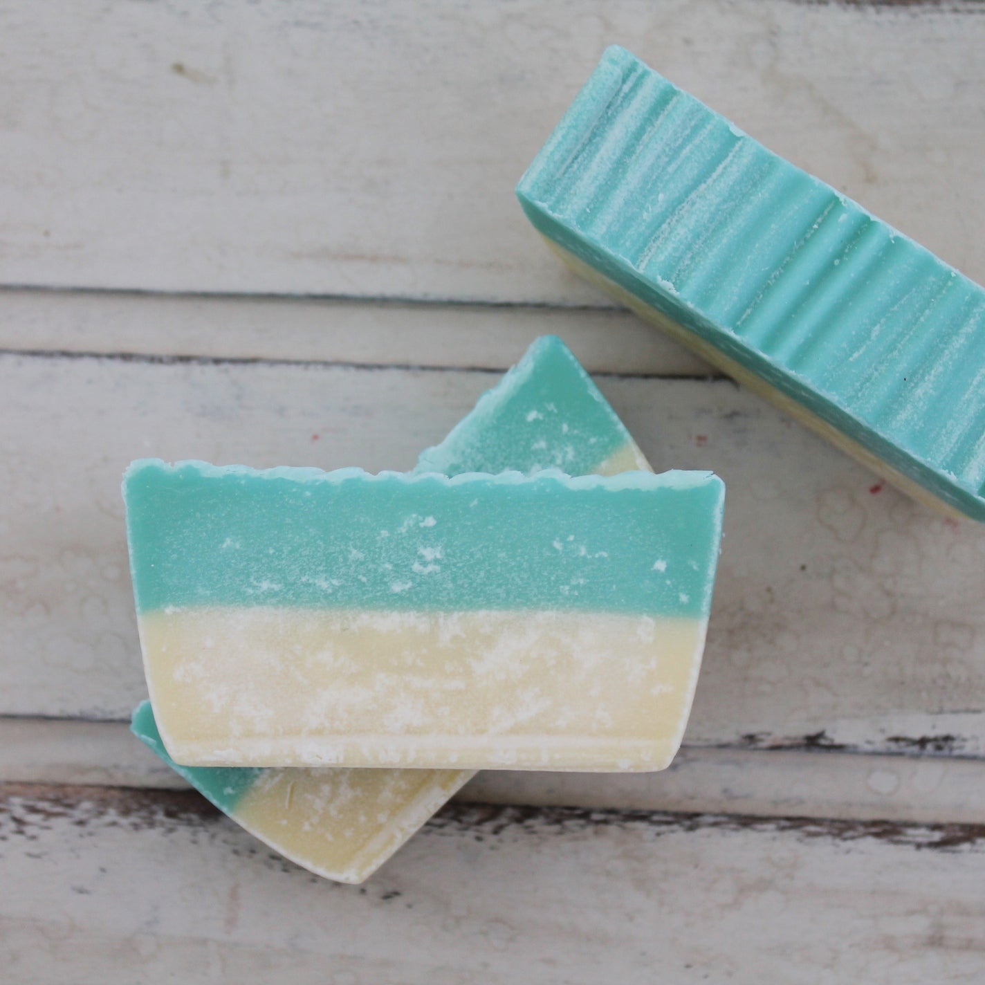 Turquoise and cream layered soap bars on whitewashed wooden background