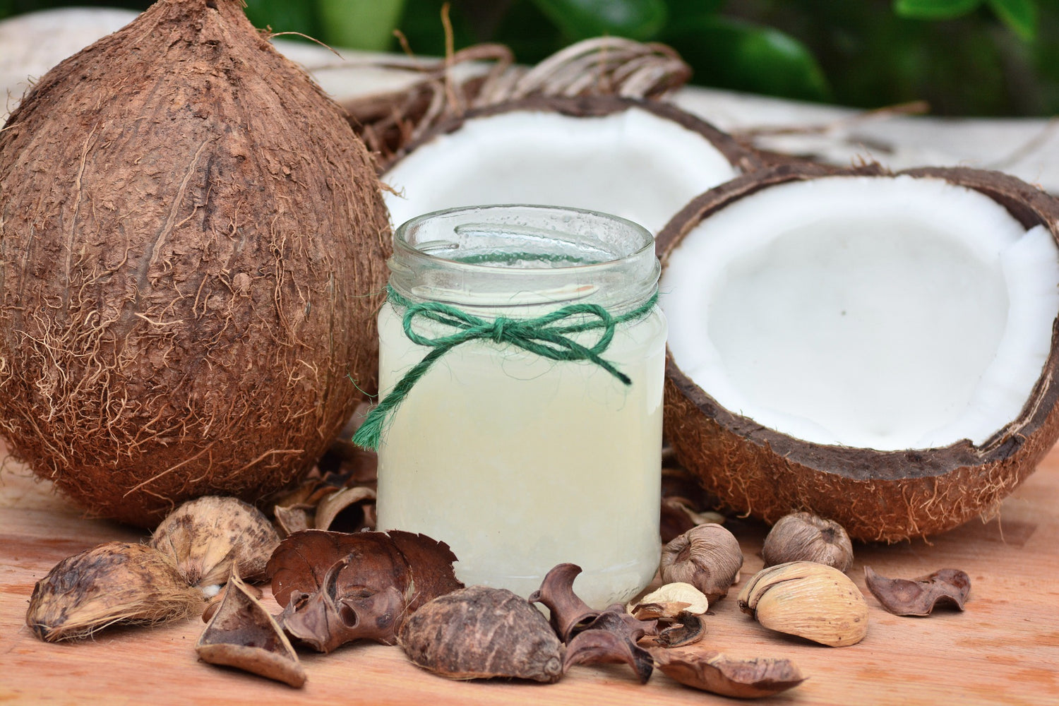 Jar of white coconut oil with coconuts in background on wooden table