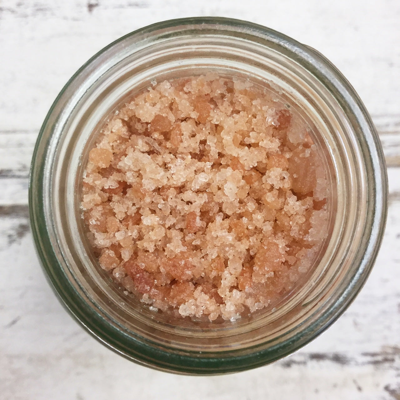 Open jar of pink bath salts viewed from above on white background