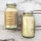 Yellow bath salts in clear bottles on whitewashed wooden background