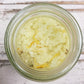 Looking down into open jar of yellow bath salts on whitewashed wooden background