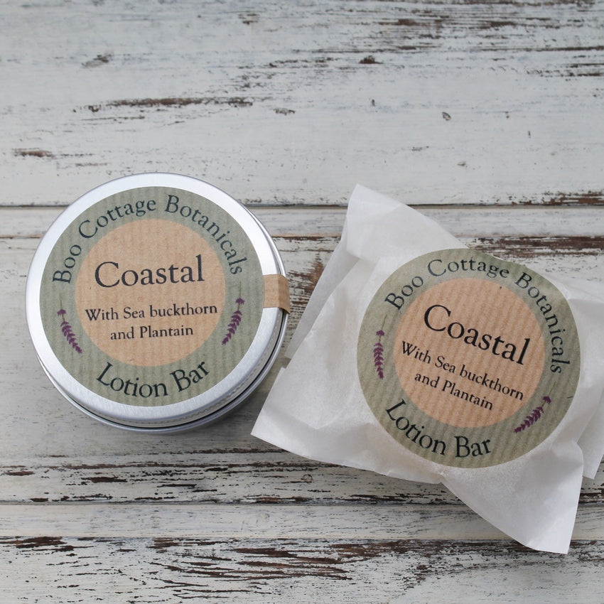 Coastal lotion bars in aluminium tin and in waxed paper bag on whitewashed wooden background