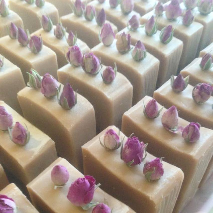 Bars of handmade pink soap with rose bud toppings stood together in rows