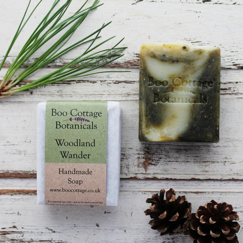 Dark green and cream marbled soap bar with wrapped bar next to it, with pine needles and pine cones